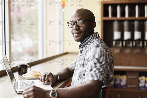 Black man using laptop in coffee shop