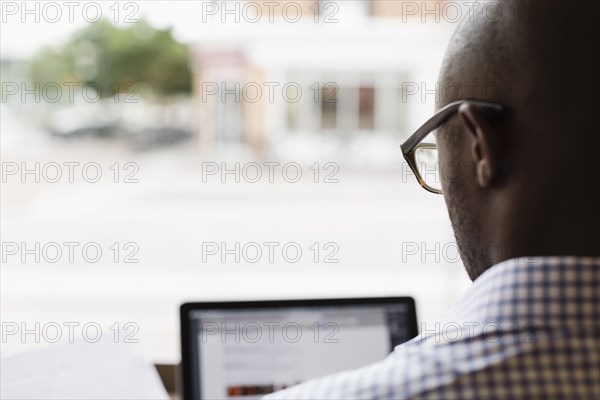 Black man using laptop at window