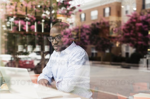 Black man using laptop in coffee shop