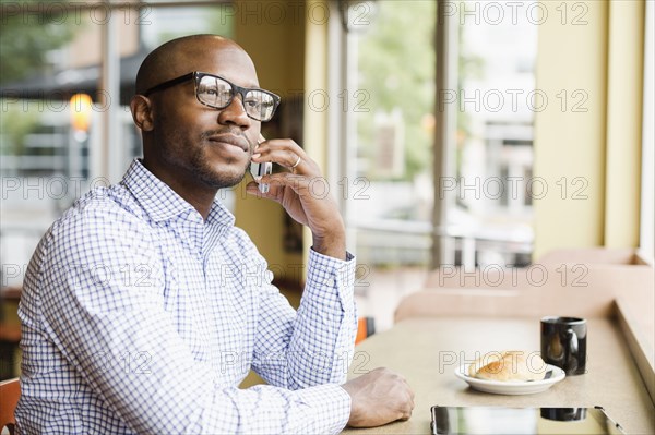 Black man talking on cell phone in coffee shop