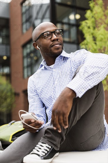 Black man listening to mp3 player in city