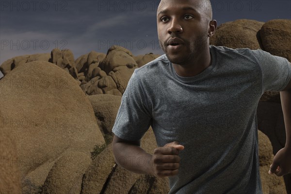 Black man running in rocky remote landscape