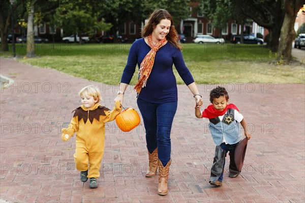 Mother and sons trick or treating together on Halloween