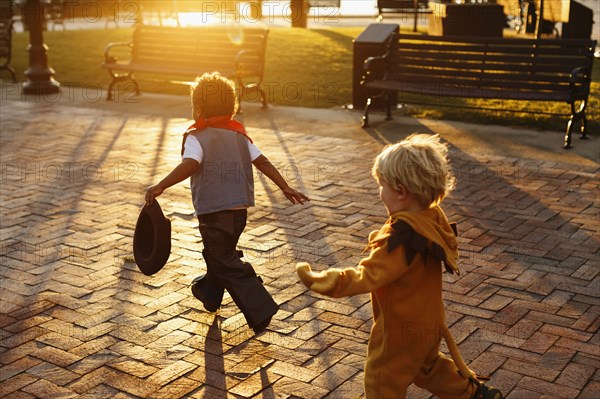 Boys playing in costumes on sidewalk