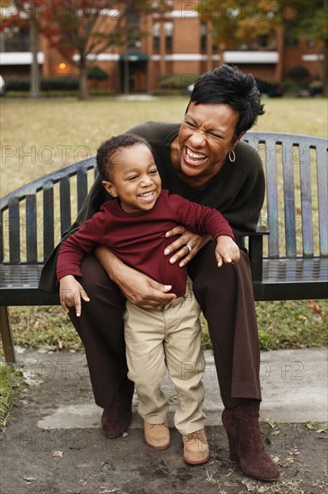 African American mother and son playing on park bench