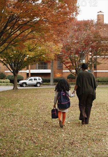 African American mother walking daughter to school