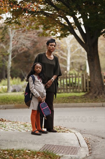 African American woman and daughter waiting for school bus