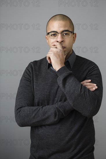 Mixed race man holding chin in hand