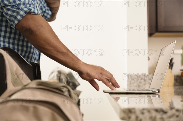 Mixed race man using laptop on counter