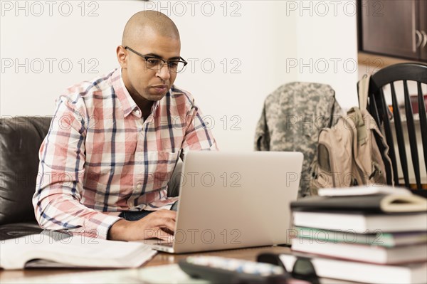 Mixed race soldier using laptop on living room sofa