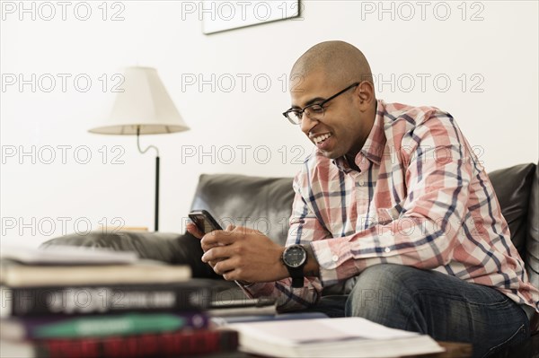 Mixed race soldier texting with cell phone on sofa