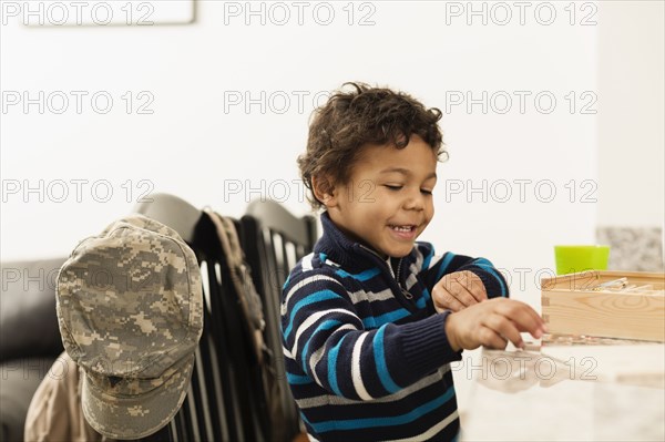 Mixed race boy playing at counter near camouflage cap