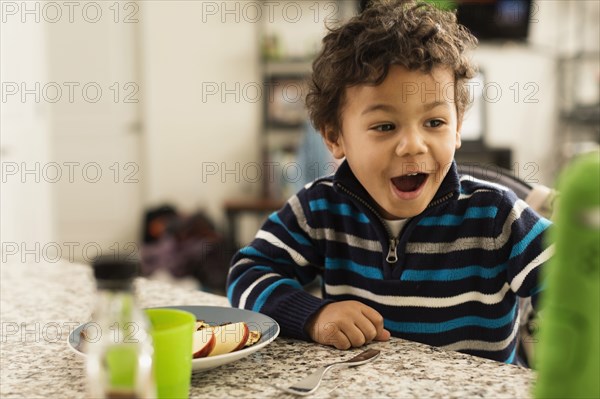 Mixed race boy eating at kitchen counter