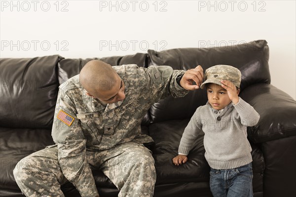 Mixed race soldier father putting cap on son