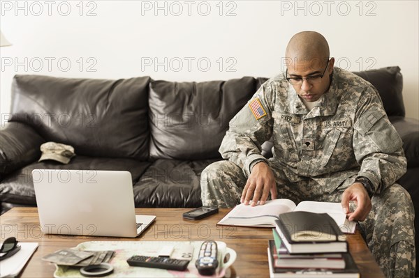 Mixed race soldier studying on sofa