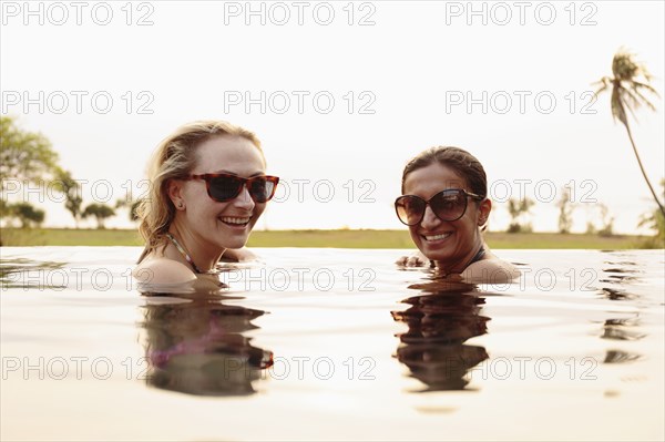 Smiling women swimming in infinity pool