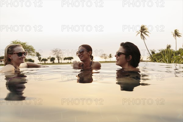 Smiling women relaxing in infinity pool