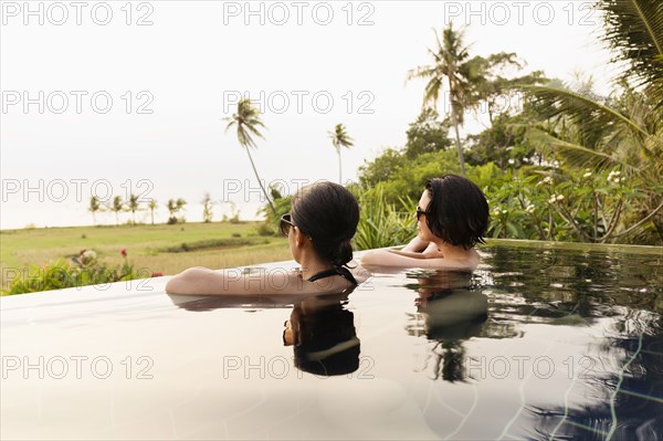 Women admiring scenic view in infinity pool