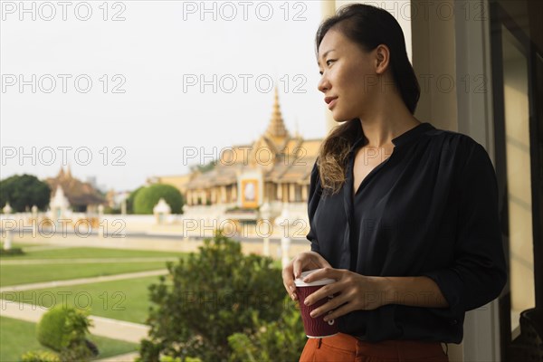 Asian businesswoman admiring view from cafe window