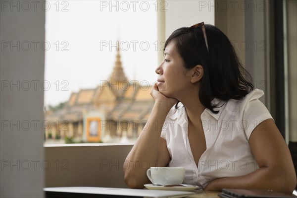 Asian woman looking out cafe window