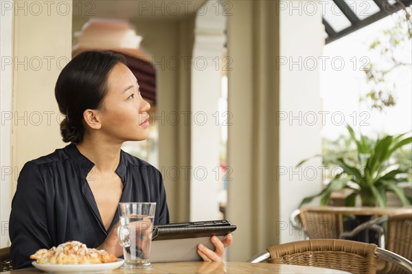 Asian businesswoman using digital tablet in cafe