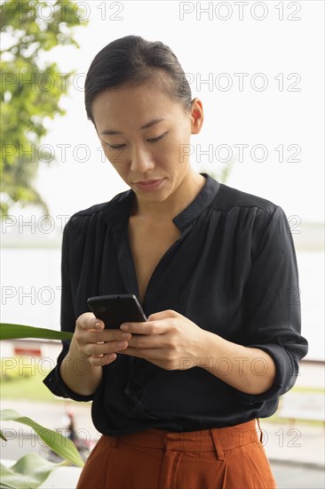 Asian businesswoman using cell phone outdoors