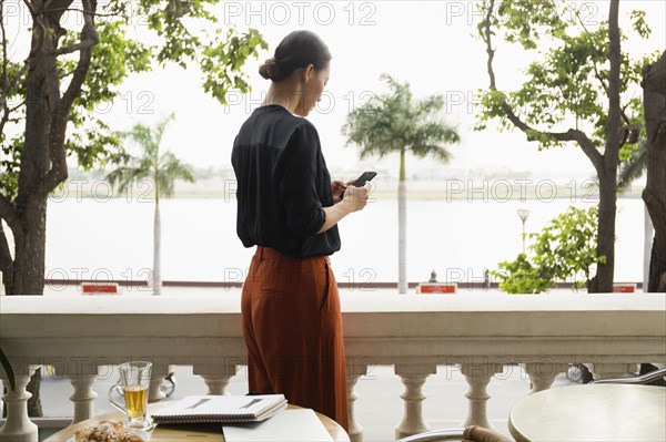 Asian businesswoman using cell phone on balcony