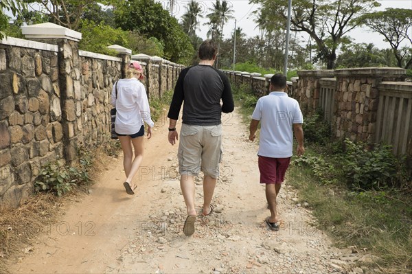 Rear view of friends walking on dirt path