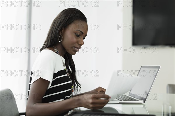 Businesswoman reading notes at office desk
