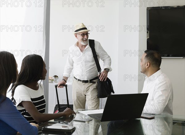 Businessman greeting colleagues in office meeting