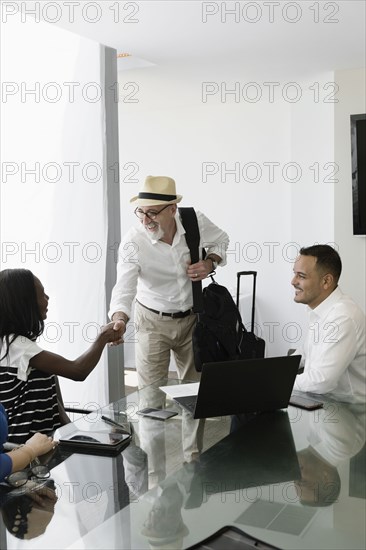 Businessman greeting colleagues in office meeting