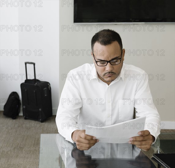 Hispanic businessman reading paperwork in office