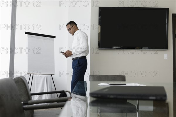 Hispanic businessman using cell phone in conference room