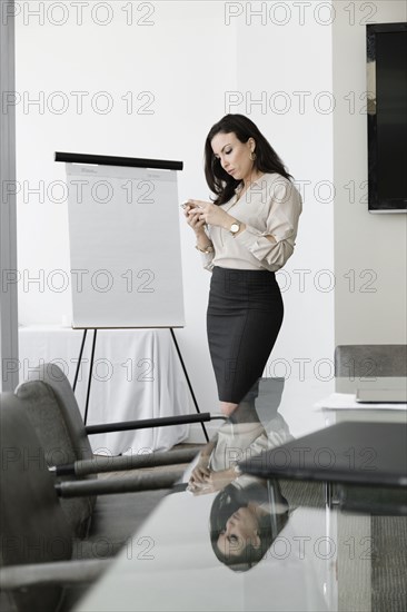 Mixed race businesswoman using cell phone in conference room