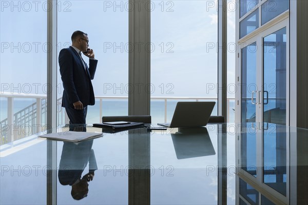 Hispanic businessman talking on cell phone in conference room