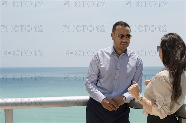 Business people talking on balcony over ocean