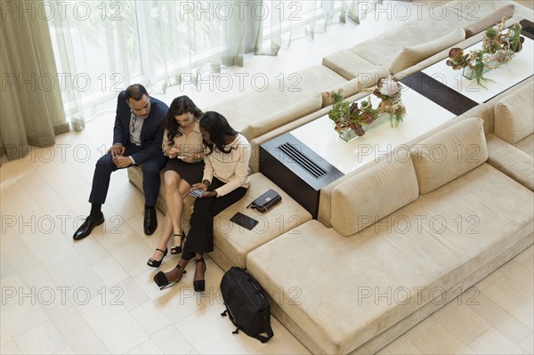 Business people using cell phones in hotel lobby