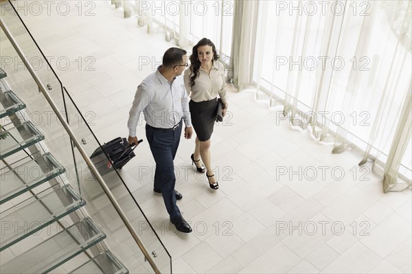 High angle view of business people rolling luggage in hotel lobby