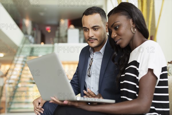 Business people using laptop in hotel lobby