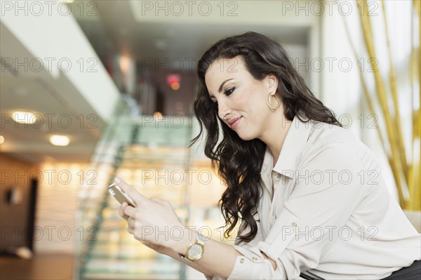 Mixed race businesswoman using cell phone in hotel lobby