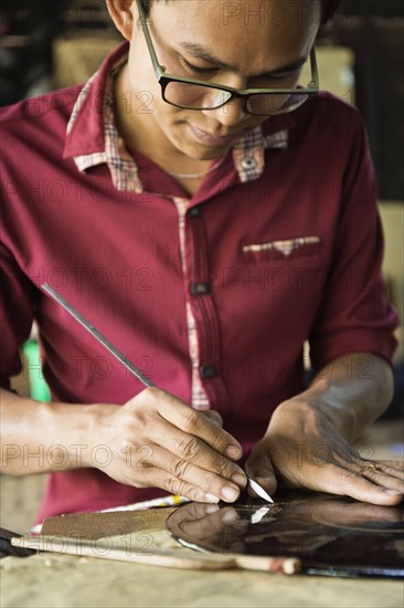 Asian artisan carving traditional design in workshop