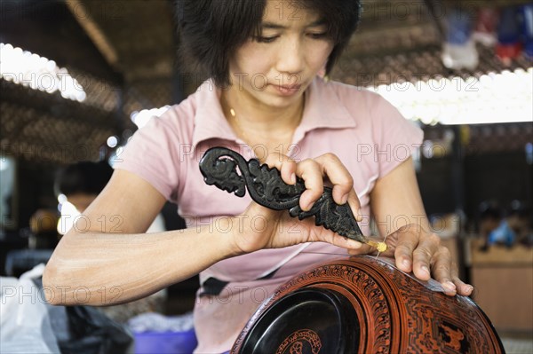 Asian artisan carving traditional design in workshop