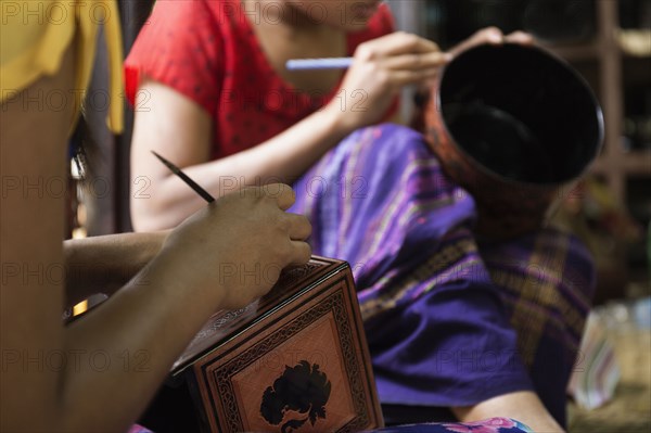 Asian artisans carving traditional design in workshop