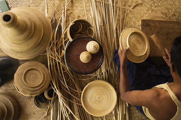 Asian artisan weaving traditional baskets in workshop