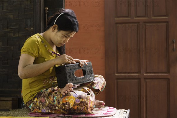 Asian artisan carving traditional design in workshop