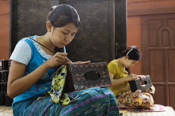 Asian artisans carving traditional design in workshop