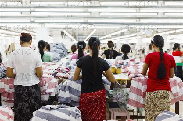 Asian workers sewing clothing in garment factory