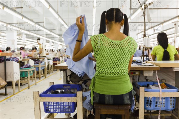 Asian worker sewing clothing in garment factory