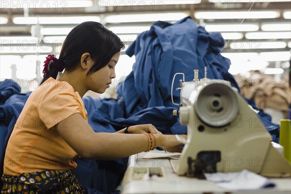 Asian worker sewing clothing in garment factory