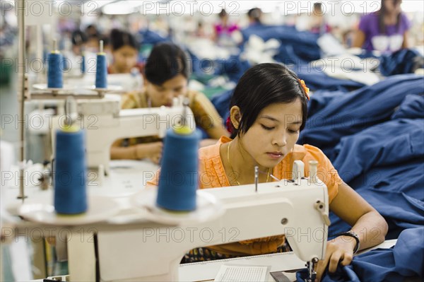 Asian worker sewing clothing in garment factory